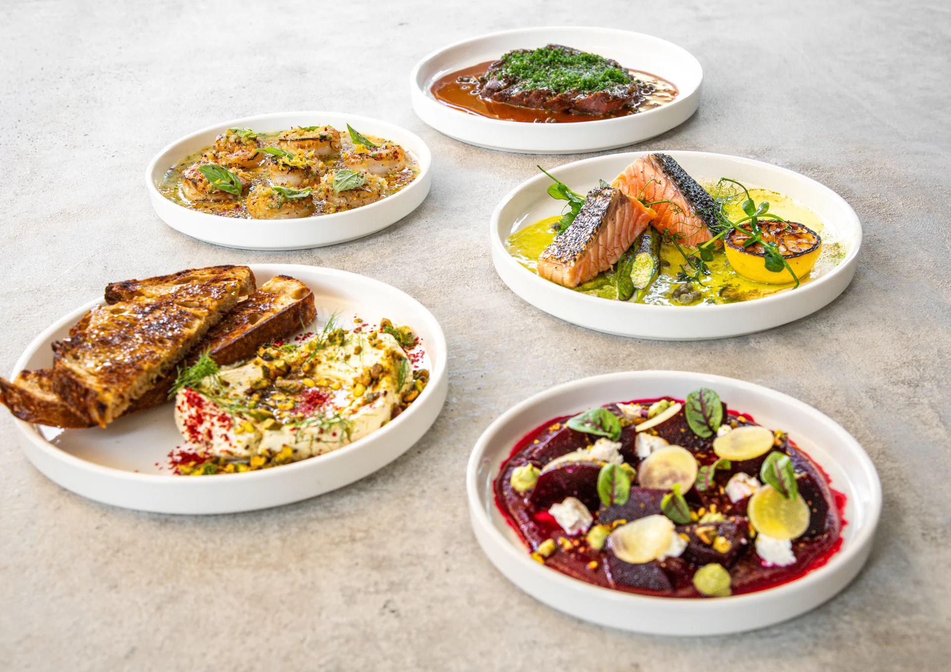 A spread of small plates with seafood, grilled bread and vegetables